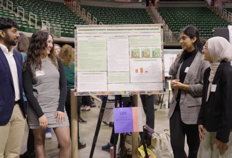 Amaya Aten at a conference with three other students presenting a poster